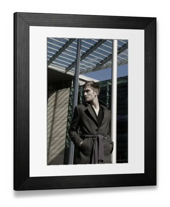 Framed Print : Young man wearing an overcoat in front of modern architecture, fashion shoot Framed Print : Young man wearing an overcoat in front of modern architecture, fashion shoot