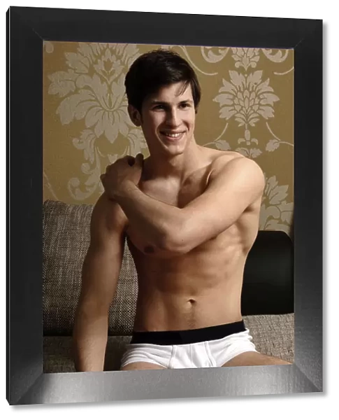 Young smiling man wearing underwear kneeling on a sofa