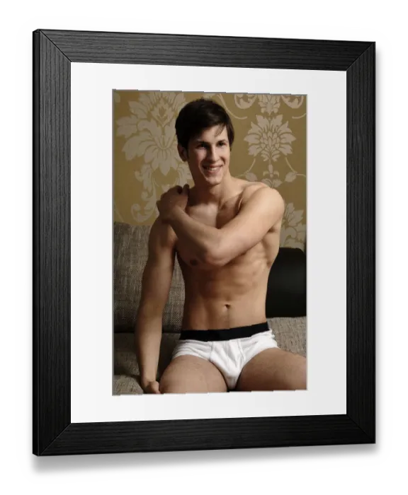 Framed Print : Young smiling man wearing underwear kneeling on a sofa Framed Print : Young smiling man wearing underwear kneeling on a sofa