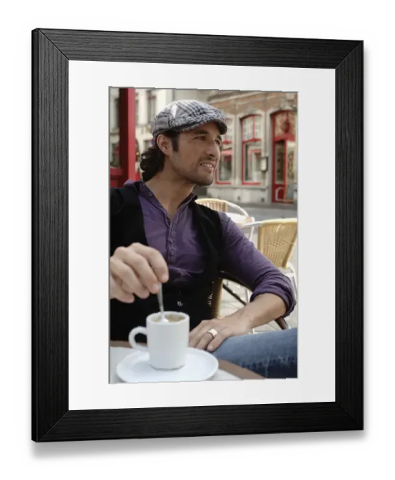 Framed Print : Man, early 30s, wearing casual clothes sitting in an outdoor cafAzA stirring a coffee cup, smiling Framed Print : Man, early 30s, wearing casual clothes sitting in an outdoor cafAzA stirring a coffee cup, smiling