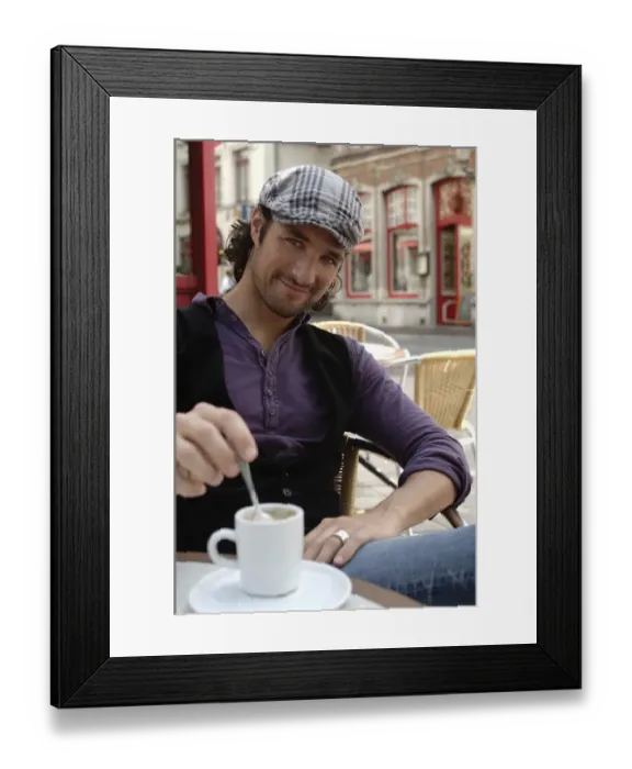 Framed Print : Man, early 30s, wearing casual clothes sitting in an outdoor cafAzA stirring a coffee cup, smiling Framed Print : Man, early 30s, wearing casual clothes sitting in an outdoor cafAzA stirring a coffee cup, smiling