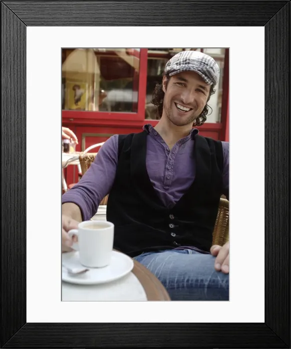 Framed Print : Man, early 30s, wearing casual clothes sitting in an outdoor cafAzA with a coffee cup, smiling Framed Print : Man, early 30s, wearing casual clothes sitting in an outdoor cafAzA with a coffee cup, smiling