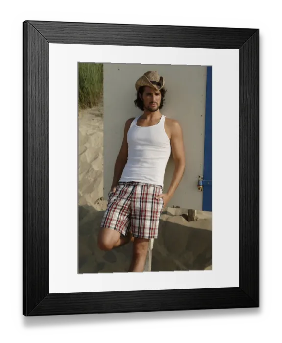 Framed Print : Man wearing a sun hat on a beach, leaning against a cottage Framed Print : Man wearing a sun hat on a beach, leaning against a cottage