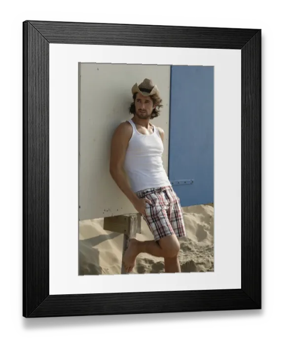 Framed Print : Man wearing a sun hat on a beach, leaning against a cottage Framed Print : Man wearing a sun hat on a beach, leaning against a cottage