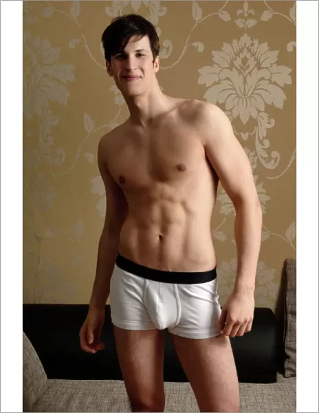Young smiling man wearing underwear standing in front of nostalgic wallpaper