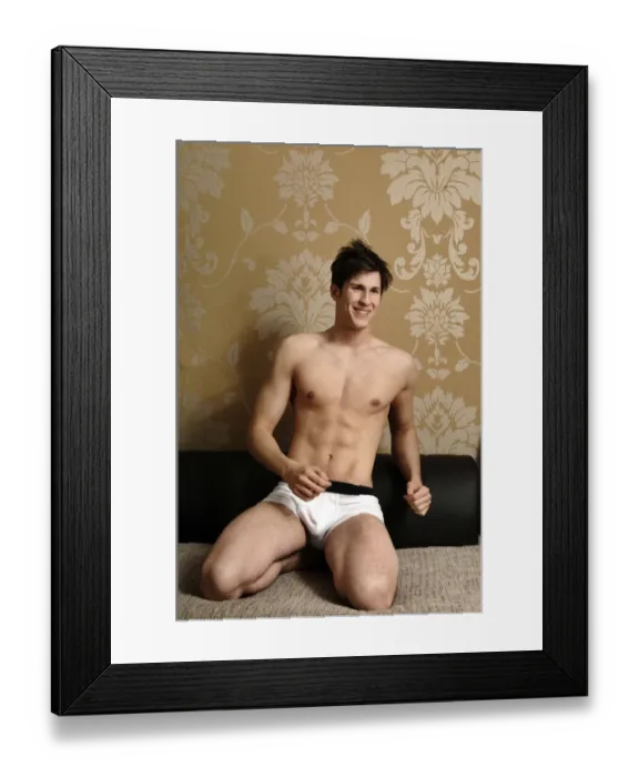 Framed Print : Young smiling man wearing underwear kneeling on a sofa Framed Print : Young smiling man wearing underwear kneeling on a sofa