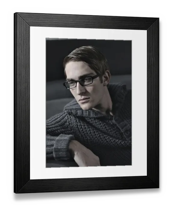 Framed Print : Young man wearing glasses sitting on a sofa