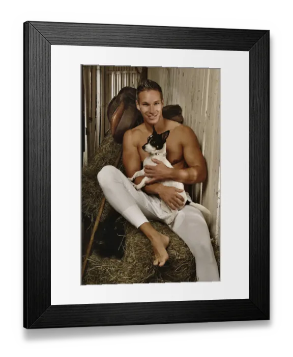 Framed Print : Man with a naked torso wearing long underwear with a dog in a horse barn sitting on bales of hay Framed Print : Man with a naked torso wearing long underwear with a dog in a horse barn sitting on bales of hay