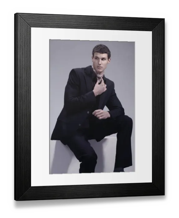 Framed Print : Fashion shot of a young man wearing a suit, sitting Framed Print : Fashion shot of a young man wearing a suit, sitting