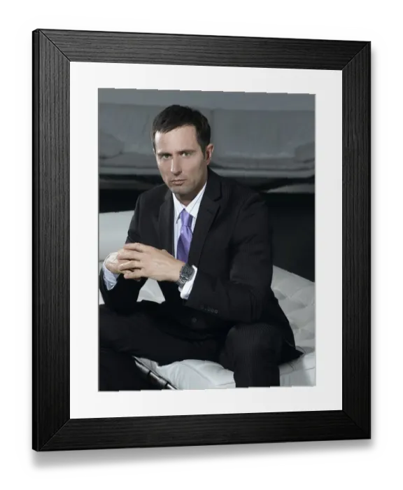 Framed Print : Businessman wearing a suit, sitting on a white sofa Framed Print : Businessman wearing a suit, sitting on a white sofa