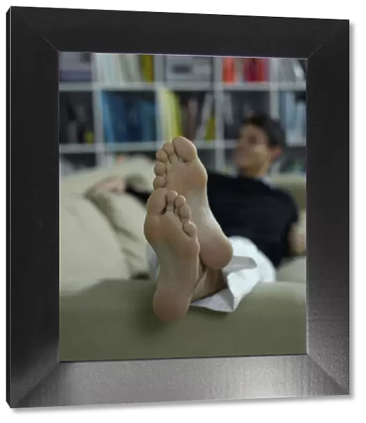 Bare feet of a man lying on a sofa