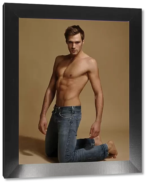 Bare-chested man in jeans, kneeling