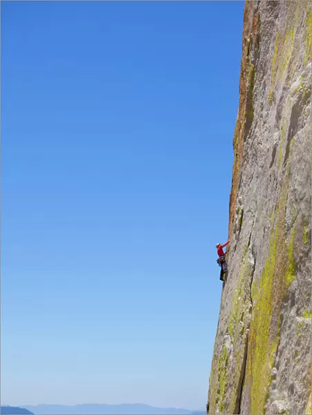 Rock climber climbing steep face of rock cliff