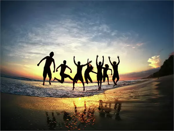 People jumping on beach at sunset in Costa Rica