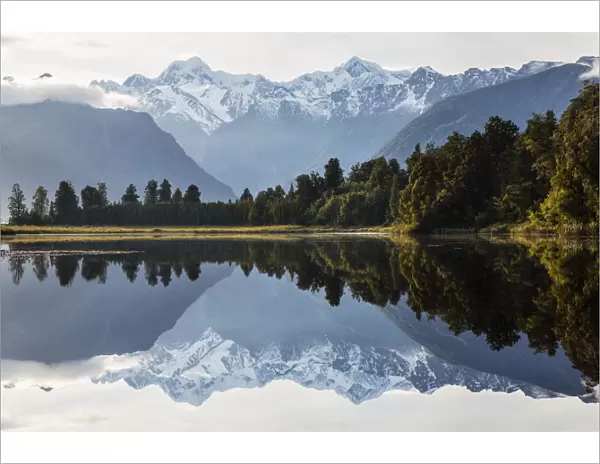 Mountains and forest reflecting in still lake, Fox Glacier, South Westland, New Zealand