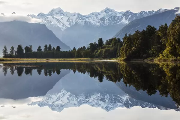 Mountains and forest reflecting in still lake, Fox Glacier, South Westland, New Zealand