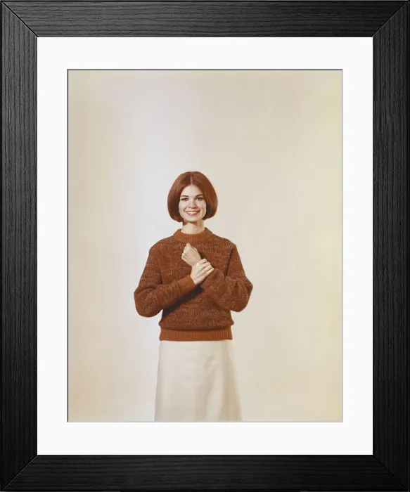 Framed Print : Young woman in jumper standing against white background Framed Print : Young woman in jumper standing against white background