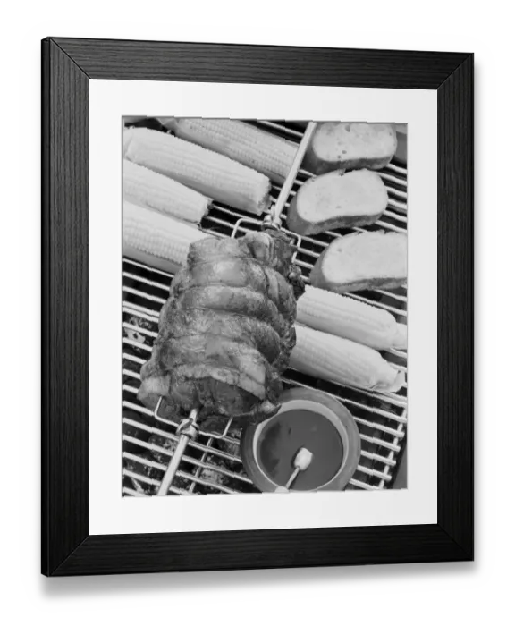 Framed Print : Spit roasting of ham on barbecue grill with corn cobs, close-up Framed Print : Spit roasting of ham on barbecue grill with corn cobs, close-up