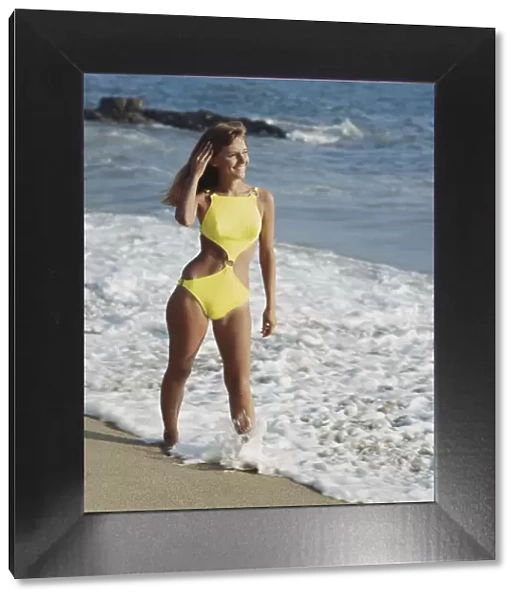 Woman in yellow swimwear standing on beach, smiling