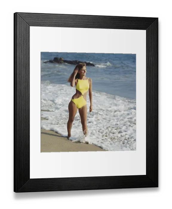Framed Print : Woman in yellow swimwear standing on beach, smiling Framed Print : Woman in yellow swimwear standing on beach, smiling