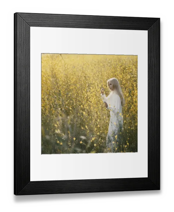 Framed Print : Young woman standing in field holding flower