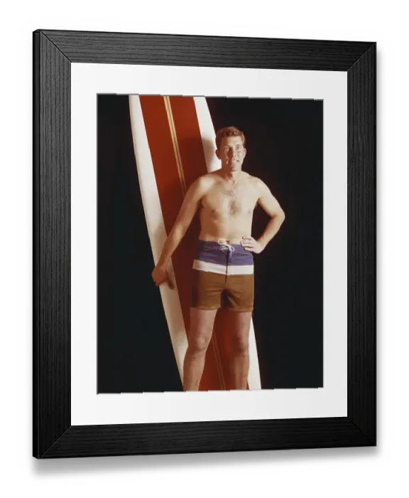 Framed Print : Mid adult man holding surfboard against black background Framed Print : Mid adult man holding surfboard against black background