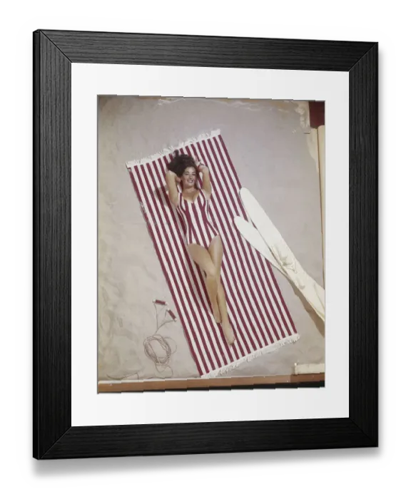 Framed Print : Young woman in striped swimwear lying on striped blanket Framed Print : Young woman in striped swimwear lying on striped blanket