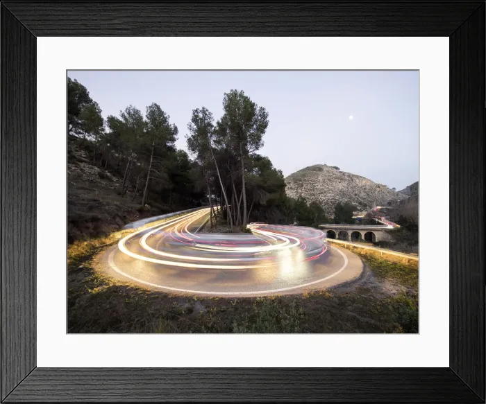 Framed Print : Lights of vehicles in movement circulating along a carretera with curves very closed in the moonlight Framed Print : Lights of vehicles in movement circulating along a carretera with curves very closed in the moonlight