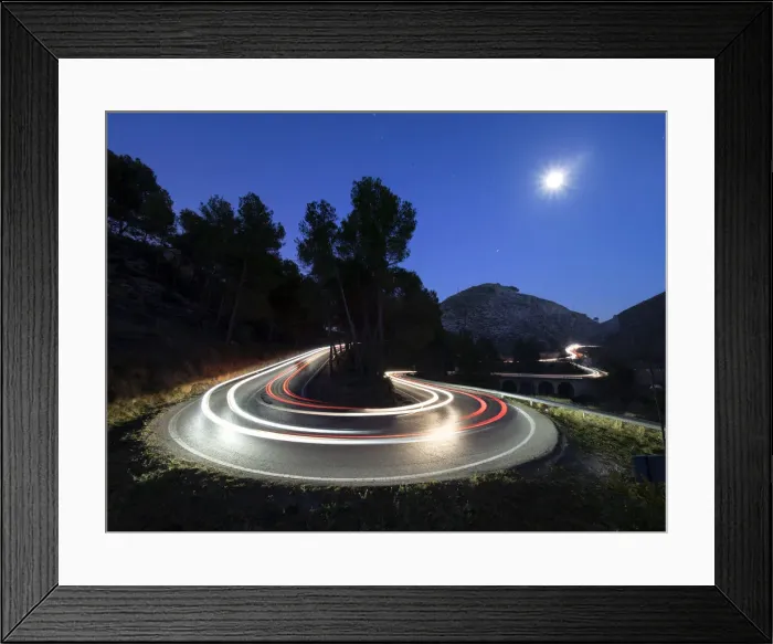 Framed Print : Lights of vehicles in movement circulating along a carretera with curves very closed in the moonlight Framed Print : Lights of vehicles in movement circulating along a carretera with curves very closed in the moonlight