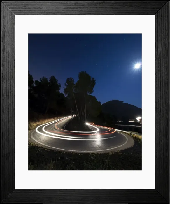 Framed Print : Lights of vehicles in movement circulating along a carretera with curves very closed in the moonlight Framed Print : Lights of vehicles in movement circulating along a carretera with curves very closed in the moonlight