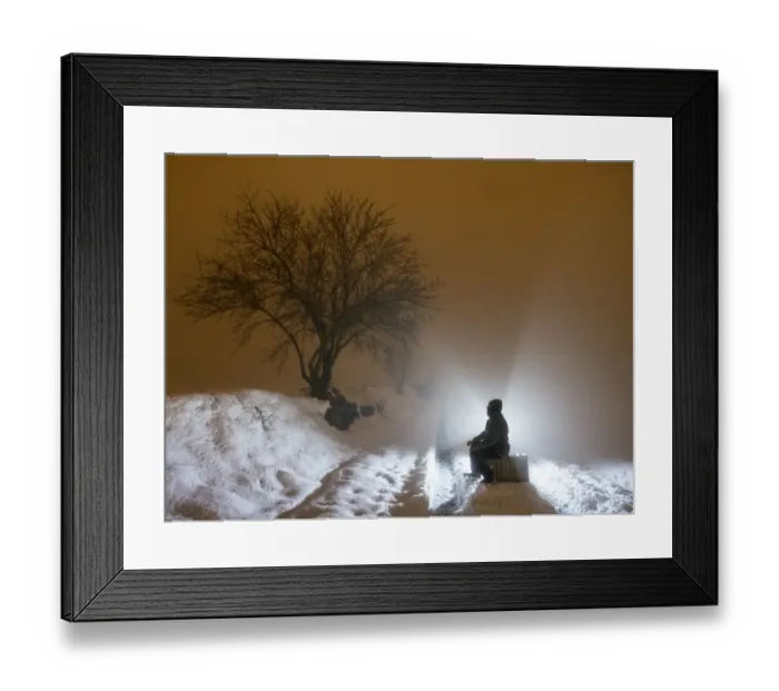 Framed Print : Silhouette of a person sitting on a suitcase resting, for a covered way of snow and fog during the night Framed Print : Silhouette of a person sitting on a suitcase resting, for a covered way of snow and fog during the night