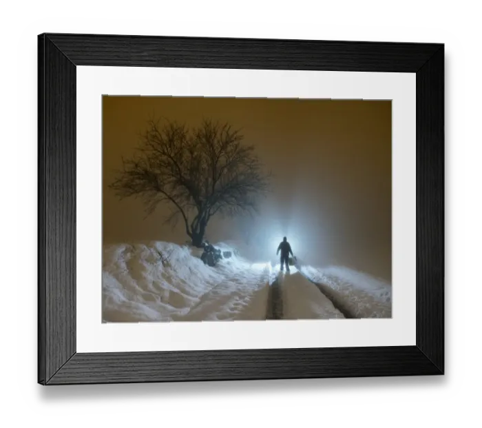 Framed Print : Silhouette of a person walking with a suitcase along a covered way of snow and fog during the night Framed Print : Silhouette of a person walking with a suitcase along a covered way of snow and fog during the night