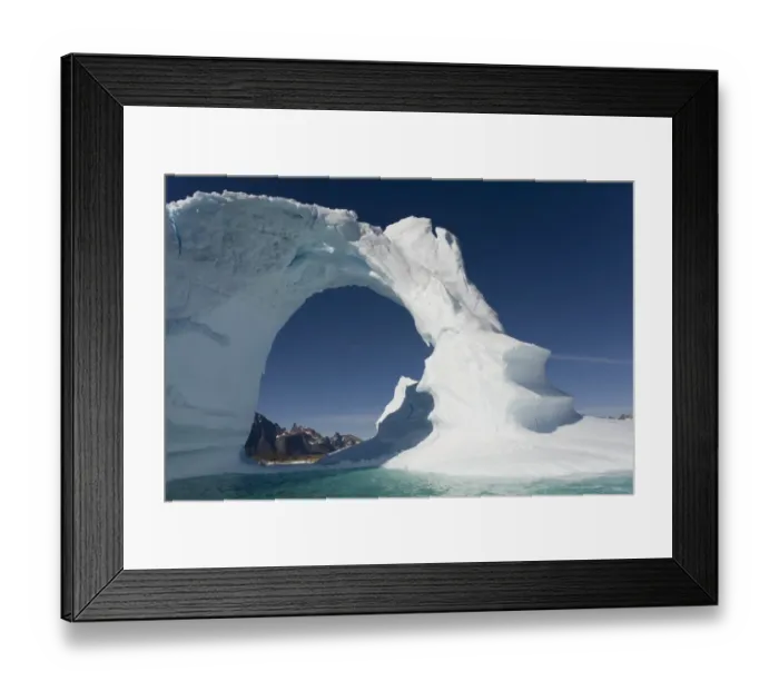 Framed Print : Greenland, Frederiksdal, Arched iceberg frames mountain peaks on Pamiagdluk Island Framed Print : Greenland, Frederiksdal, Arched iceberg frames mountain peaks on Pamiagdluk Island