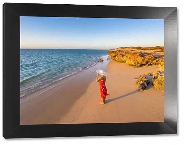 Woman with red dress on Osprey Bay beach at sunset. Western Australia