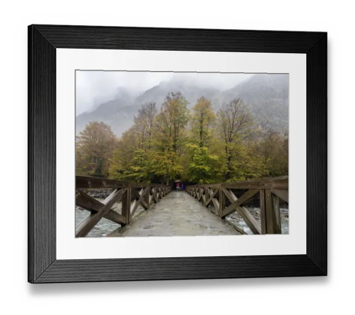 Framed Print : Persons with umbrellas that walk on a bridge of wood that crosses a river in a forest in autumn Framed Print : Persons with umbrellas that walk on a bridge of wood that crosses a river in a forest in autumn