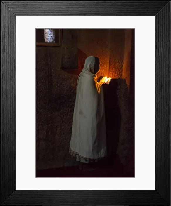 Framed Print : Prayers. A woman reads the bible under the light of a candle in Bet Medhane Framed Print : Prayers. A woman reads the bible under the light of a candle in Bet Medhane
