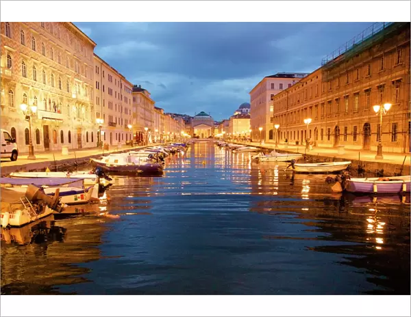 Grand canal with boats at night in Trieste, Italy