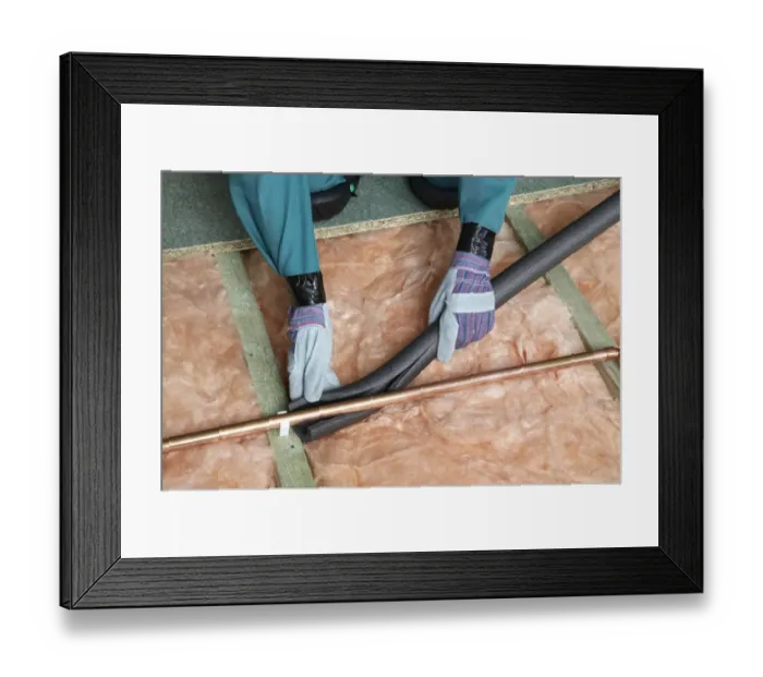 Framed Print : Attaching pipe insulation to a copper pipe above joists and insulation blanket Framed Print : Attaching pipe insulation to a copper pipe above joists and insulation blanket