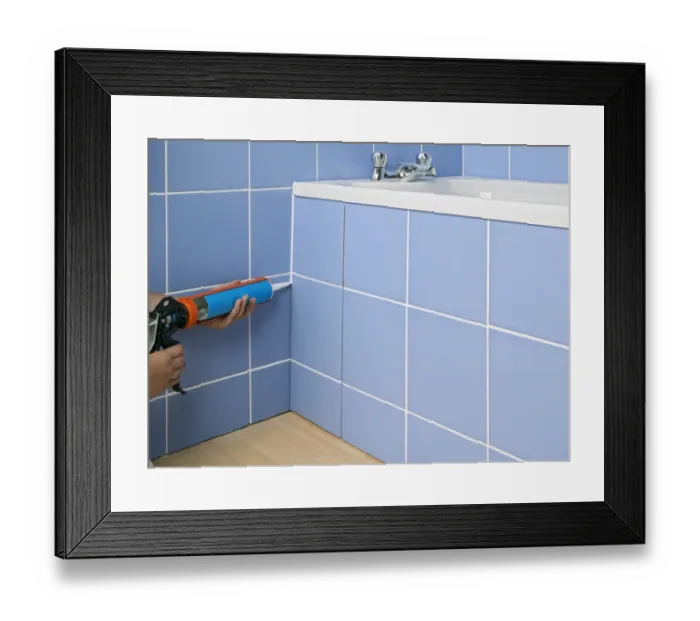 Framed Print : Hands applying sealant to side of bath Framed Print : Hands applying sealant to side of bath