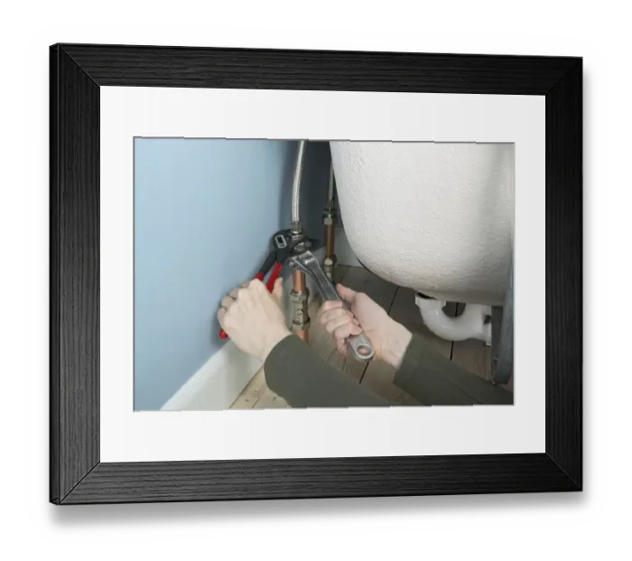 Framed Print : Tightening flexible connectors attached to a bath with an adjustable spanner and grips, close up