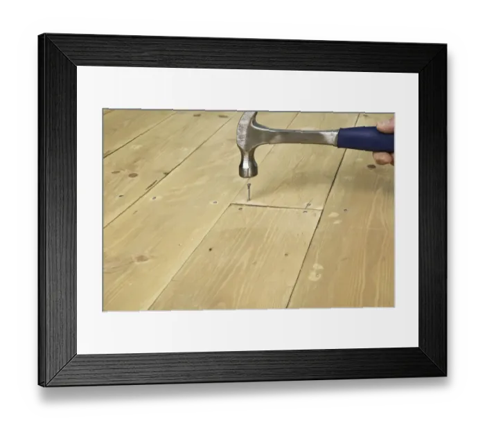 Framed Print : Hammering a nail in to a floor board Framed Print : Hammering a nail in to a floor board