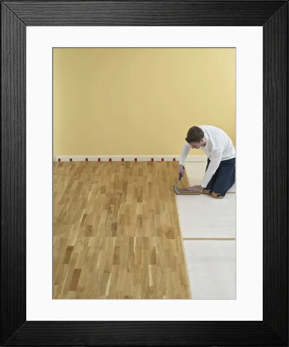 Framed Print : Man kneeling and holding hammer over floorboards
