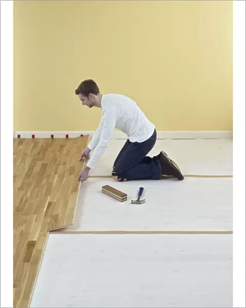Man kneeling and holding floorboard