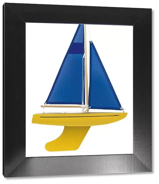 Yellow toy sailing boat with blue sail, front view