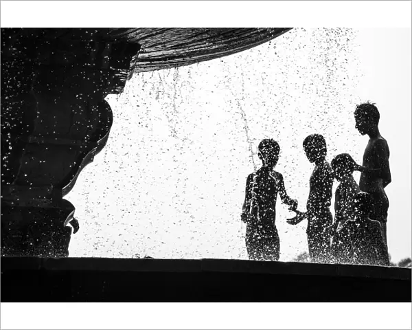 Too Hot. Many boys relax from hot air by water fountain in the Delhis public park