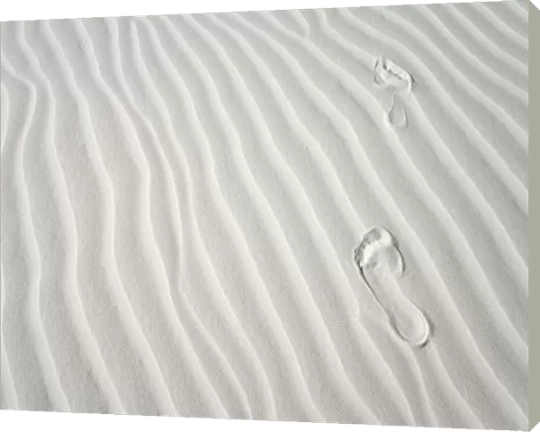 Footprints of barefoot hiker on white gypsum sand dune