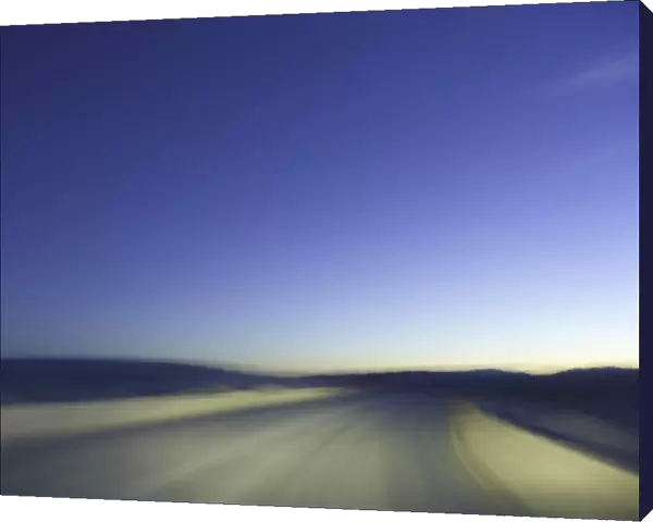 Sand road through dunes, lit by headlights, night (blurred motion)