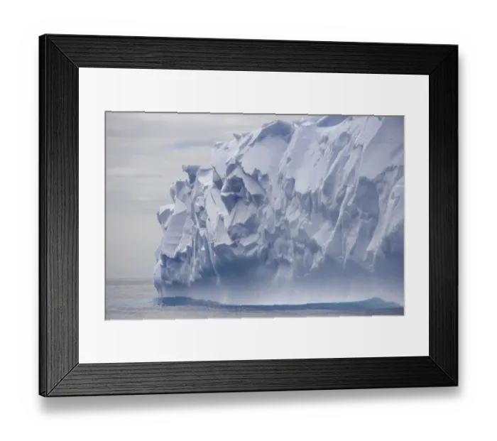 Framed Print : Blue iceberg carved by waves floats in calm sea Framed Print : Blue iceberg carved by waves floats in calm sea
