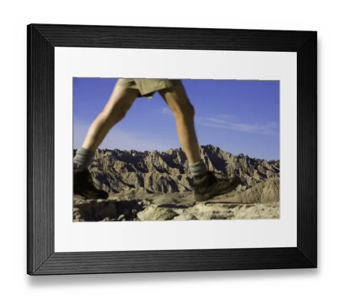 Framed Print : Male hiker walking in badlands, low section (focus on rock formations) Framed Print : Male hiker walking in badlands, low section (focus on rock formations)