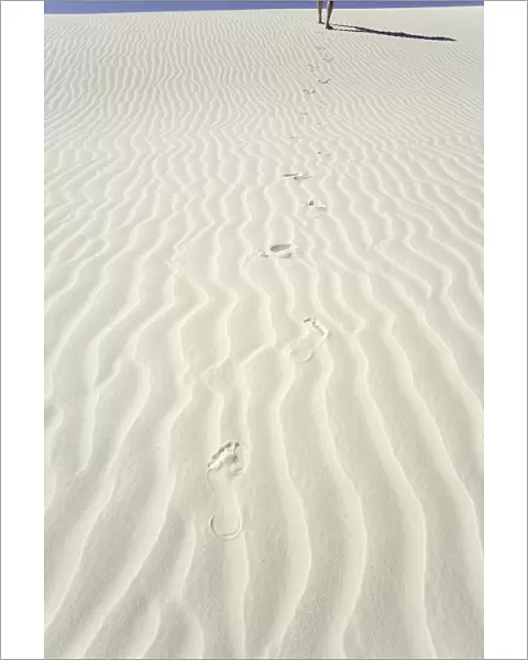 Mature man leaving footprints on white gypsum sand dune, low section